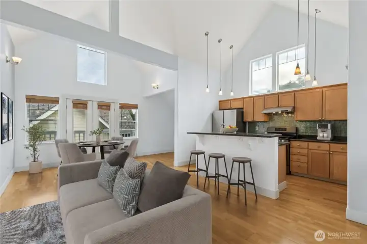 Open-concept living, dining, and kitchen area with soaring vaulted ceilings and abundant natural light.