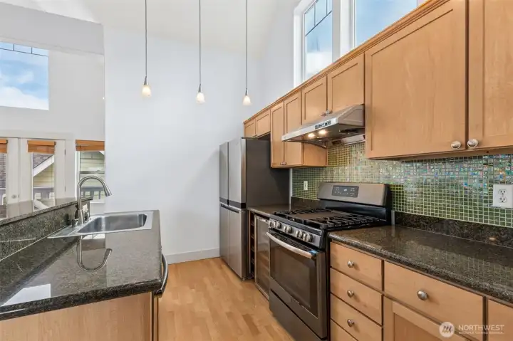Open kitchen with breakfast bar seating overlooking the bright living space with vaulted ceilings.