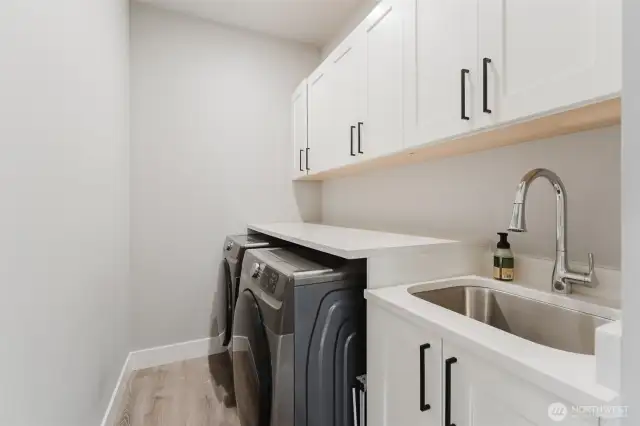 Dedicated laundry room with utility sink, lots of folding space, and extra storage
