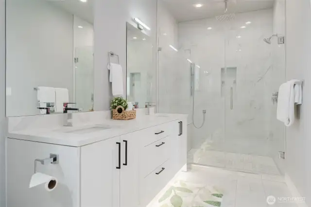 Primary bathroom includes large double vanity and tiled walk in shower