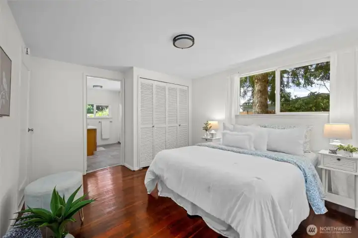 Wake up to nature just outside your window in this calming primary ensuite bedroom with hardwood floors, ample closet space, and soft natural light.