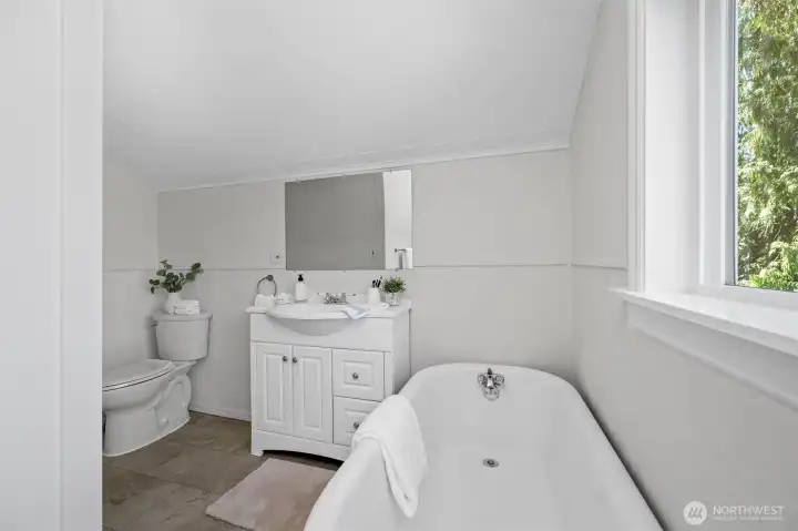 Relax and unwind in the vintage-style upstairs bathroom, complete with a classic clawfoot tub and a view of the trees outside.