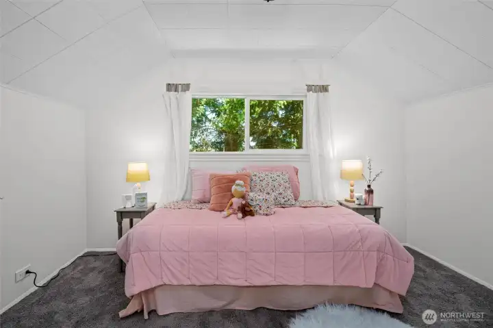 A cheerful upstairs bedroom with dormer ceilings and a peaceful view.