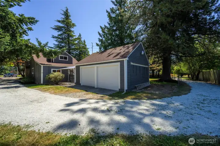 Ample parking and storage with a detached two-car garage, complemented by a circular gravel driveway and a covered breezeway leading to the home.