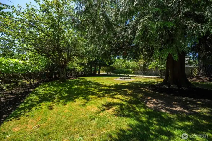 Mature landscaping, fruit trees, and cedar provide shade and serenity in the fenced backyard.
