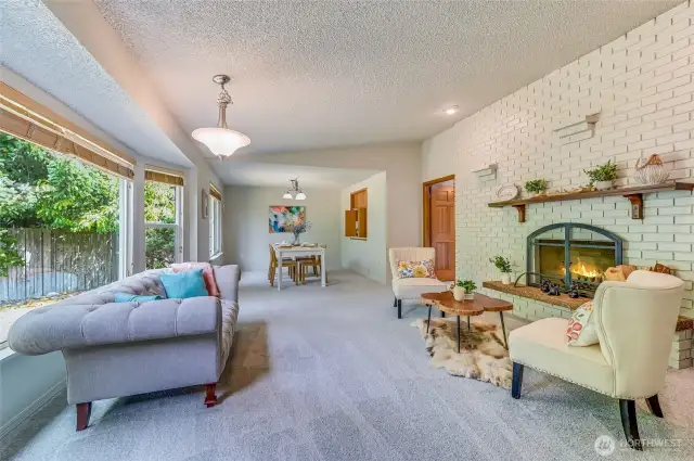 To the left of the entryway we find the Living Room with vaulted ceiling. Wood burning fireplace with seating and mantle make a warm and welcoming space to gather. This room features new carpet and fresh paint (the whole house does).