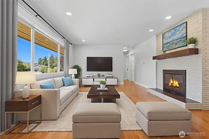 Virtually staged living room with picture windows, cozy white brick enclosed fireplace.