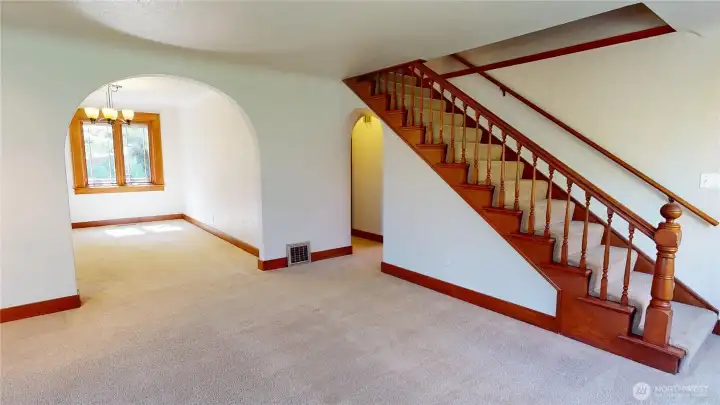 Living room looking towards arched doorway to dining room and stairs to second level. Original hardwood floors are beneath the wall to wall carpet.  This home has been maintained in "Period Perfect" condition with the coved ceilings and arches.