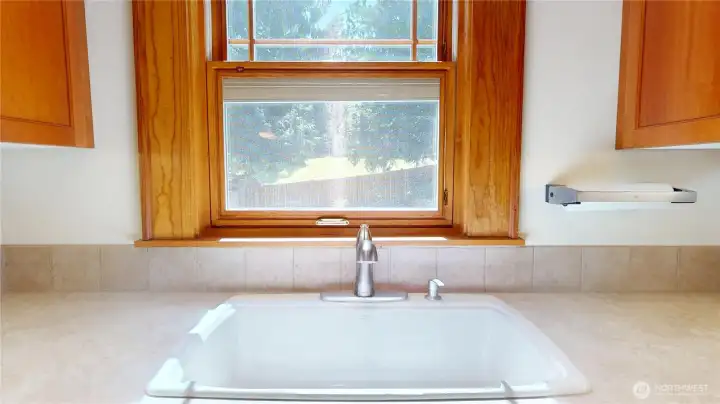Kitchen sink window overlooks the fully landscaped private backyard landscape.  The windows in this area of the home are custom with built in screens and built in louvered shades between the glass.
