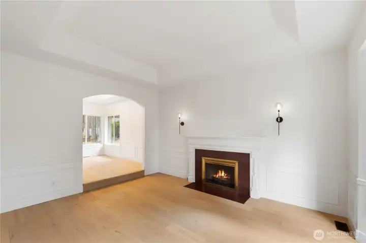 Living room has arched entries, vaulted ceilings, wainscoting & gas fireplace.