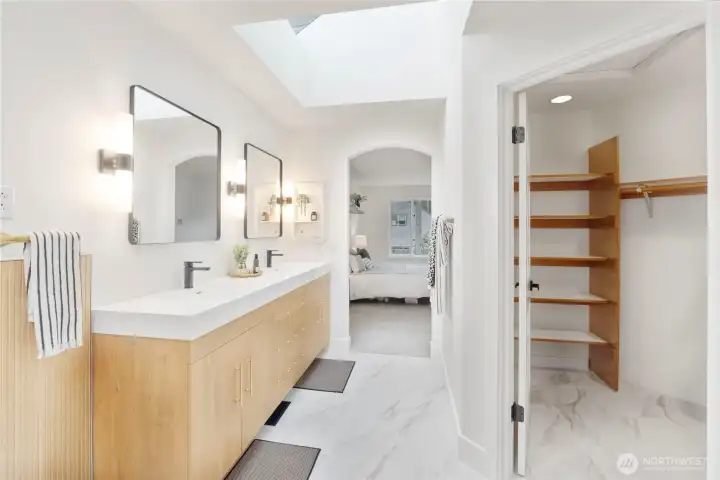 Tastefully remodeled primary bathroom with double sink vanity, separate shower and soaking tub, walk-in closet, & skylights.