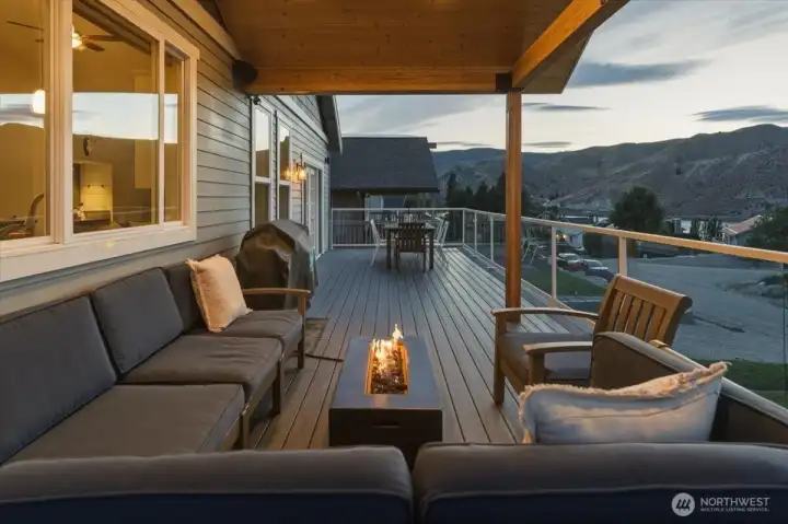 Twilight view of outdoor living area with lounge area with fire table and outdoor dining and BBQ area.