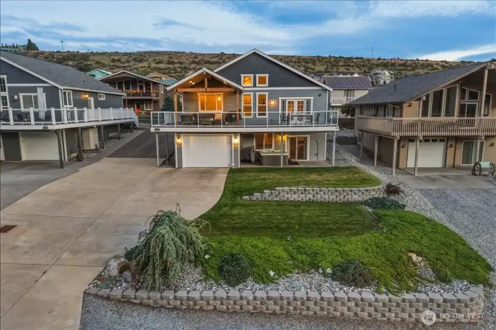 Twilight view of home with grassy front lawn, large garage and oversized driveway.