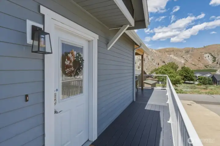 View of front door and wraparound Trex deck with glass railings.