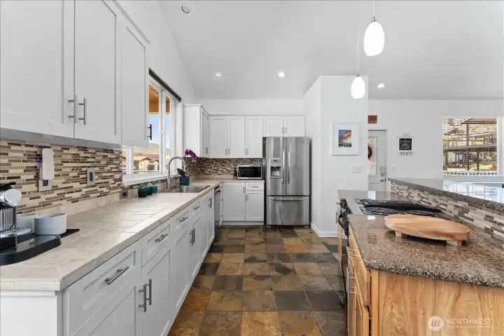 View 1 of kitchen with river and mountain views, slate tile flooring, tile and granite countertops and stainless steel appliances.