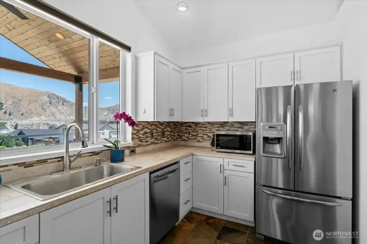 View 2 of kitchen with river and mountain views, slate tile flooring, tile and granite countertops and stainless steel appliances.
