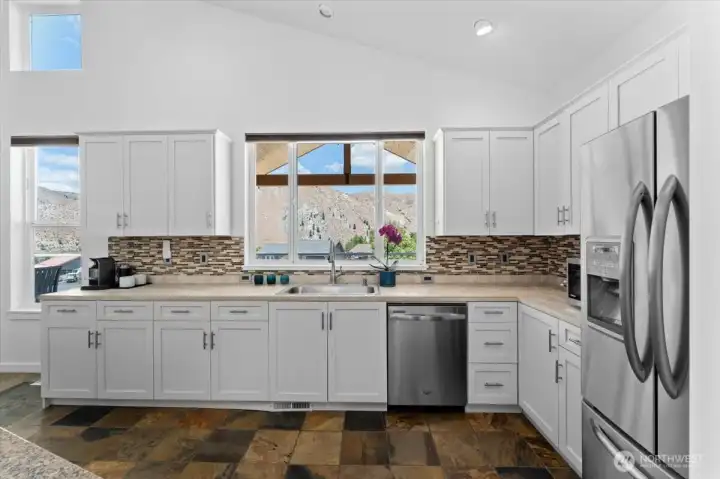 View 3 of kitchen with river and mountain views, slate tile flooring, tile and granite countertops and stainless steel appliances.