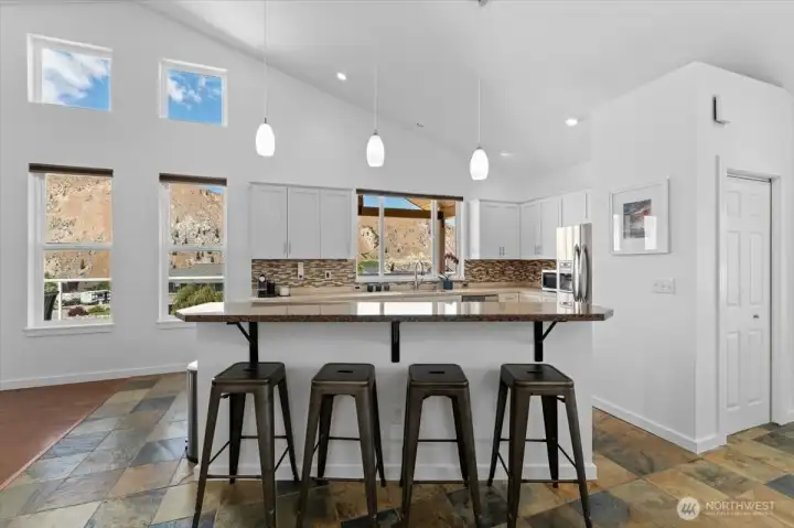View of kitchen with river and mountain views, sit up bar, slate tile floors, vaulted ceilings and brand new interior paint.