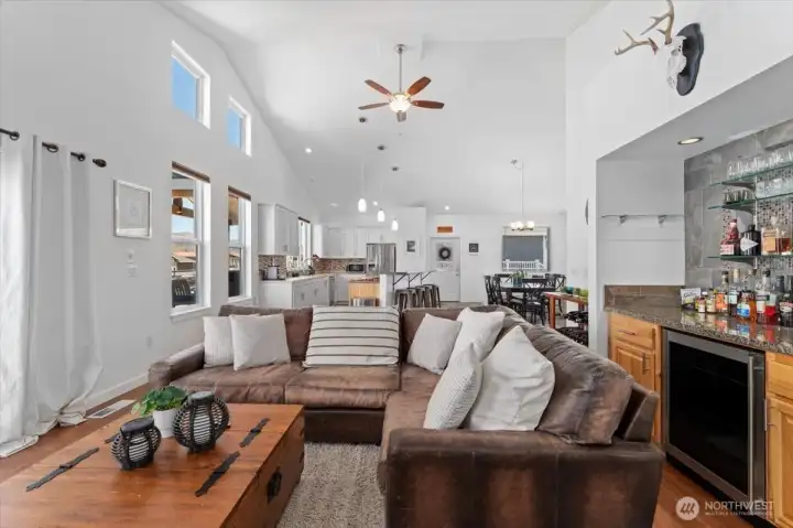 View 1 of Living Room with mini bar and beverage fridge looking towards the kitchen, dining room and entryway.