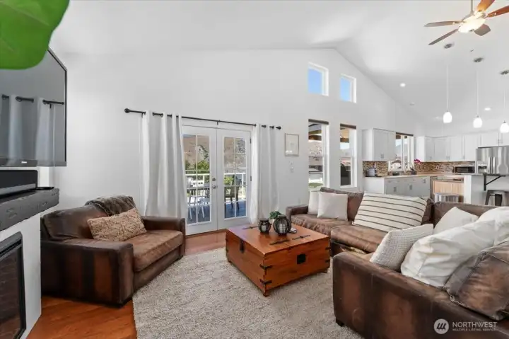 View 3 of Living Room with electric fireplace, mini bar with beverage fridge, board and batten accent wall and French doors leading to the outdoor river and mountain view deck and outdoor living area.
