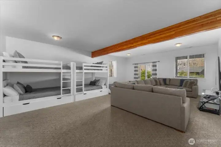 View 1 of Lower Level Bonus/Media room with bunk beds and sliding glass doors leading to the Lower Level outdoor living area with private hot tub and grassy front yard.