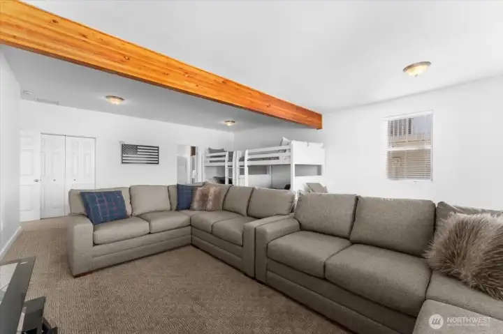 View 3 of Lower Level Bonus/Media room with bunk beds and sliding glass doors leading to the Lower Level outdoor living area with private hot tub and grassy front yard.