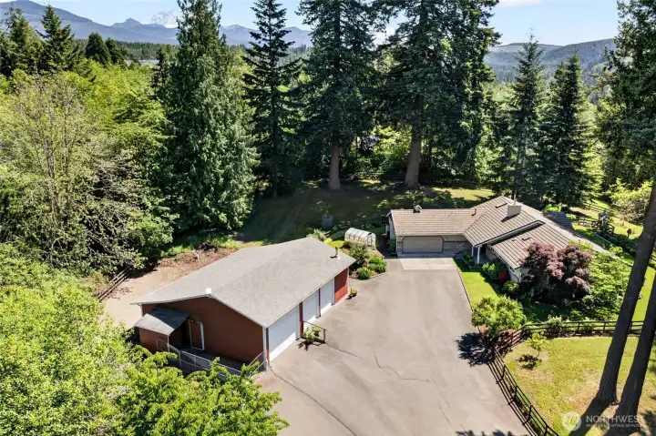 Aerial view of this well-designed property showcasing the spacious shop/barn, dog kennel, paved driveway, and abundant parking. Plenty of room for RVs, boats, trailers, and all your toys, with easy access throughout the property.