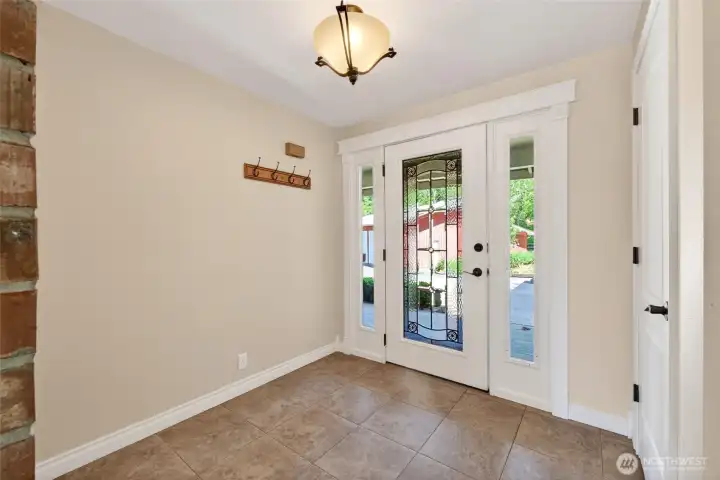 Step inside to a welcoming entry featuring beautiful tile flooring, a leaded glass front door, and abundant natural light that fills the space with warmth and charm.