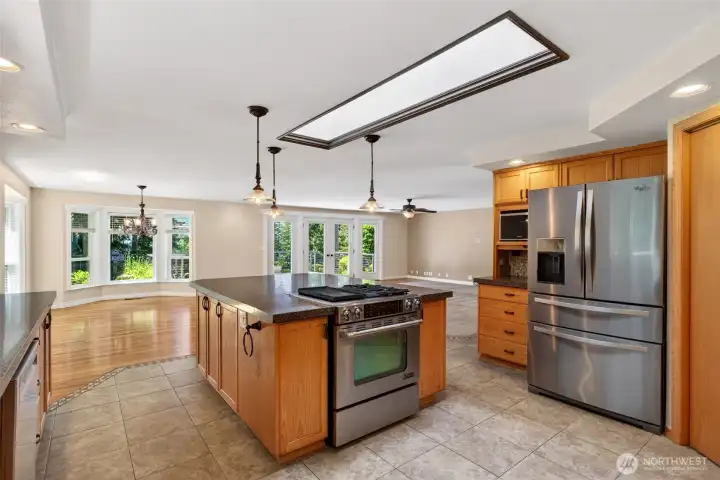 Natural light pours in through skylights, highlighting the kitchen’s beautiful tile floors and stainless gas cooktop for a space that is both stylish and highly functional.