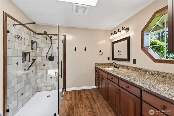 The primary ensuite bathroom features a glass-enclosed shower and granite countertops, offering both style and functionality.