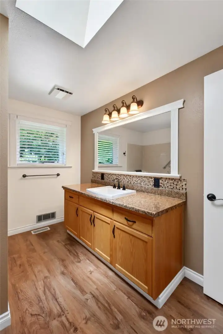 The spacious full guest bathroom is beautifully brightened by a skylight, creating a light-filled and welcoming atmosphere.