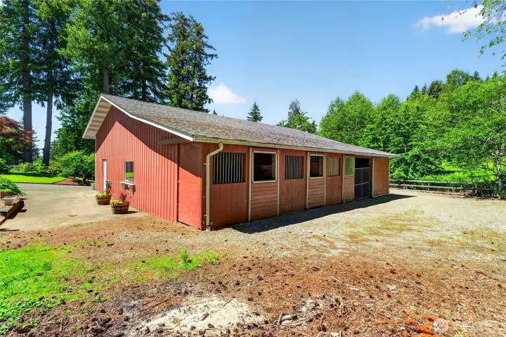 The back of the shop offers three stalls designed for versatility, including a third stall set up as a grooming and wash rack with on-demand hot water and dog grooming capability. A separate bay provides additional storage for equipment or hay.
