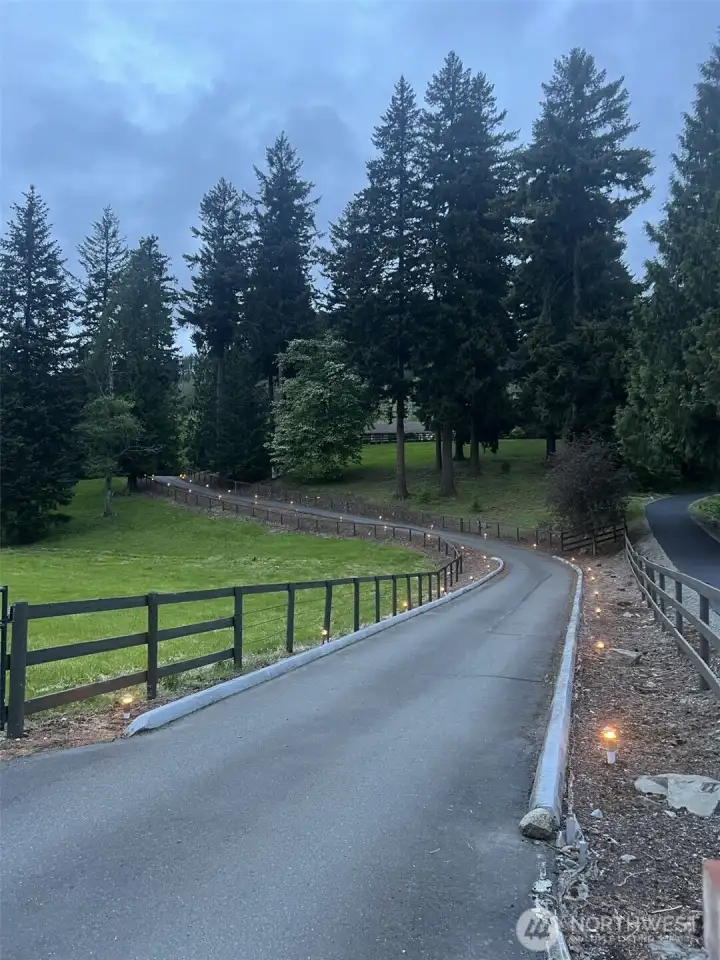 As evening falls, subtle lighting illuminates the driveway, creating an elegant and inviting approach to the home.