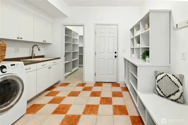Winding back around the kitchen you find  the roomy laundry room/mud-room with amazing cabinetry storage, ample shelving and a handy sink too.