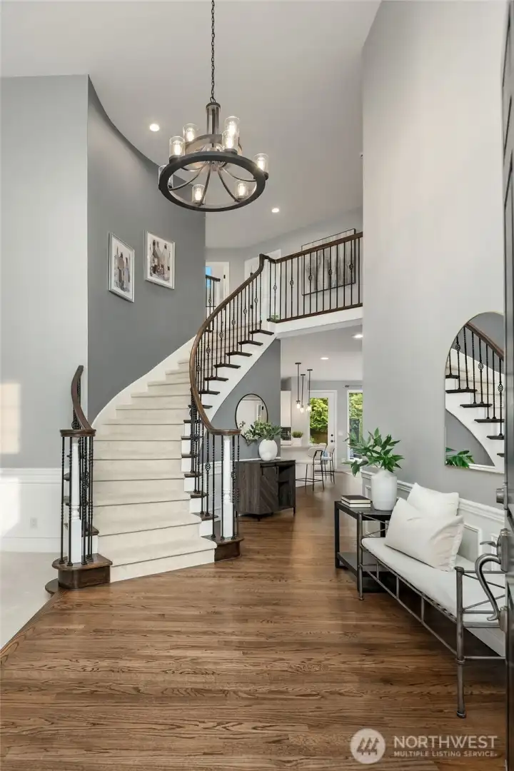 A soaring two-story foyer with a sweeping curved staircase makes a stunning first impression, while rich hardwoods add warmth and elegance to the space.