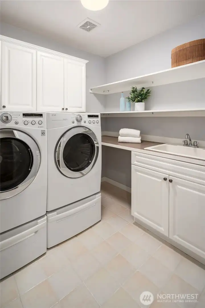 Thoughtfully designed laundry room with a tile floor, side-by-side washer/dryer, utility sink, and plenty of storage for all your essentials. All appliances are included with this home.