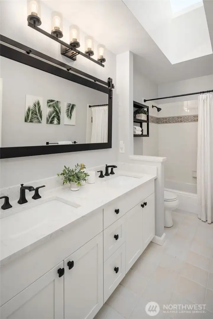 The updated upper level bathroom features dual sinks, a quartz countertop, tile flooring and a shower/tub with tile surround.
