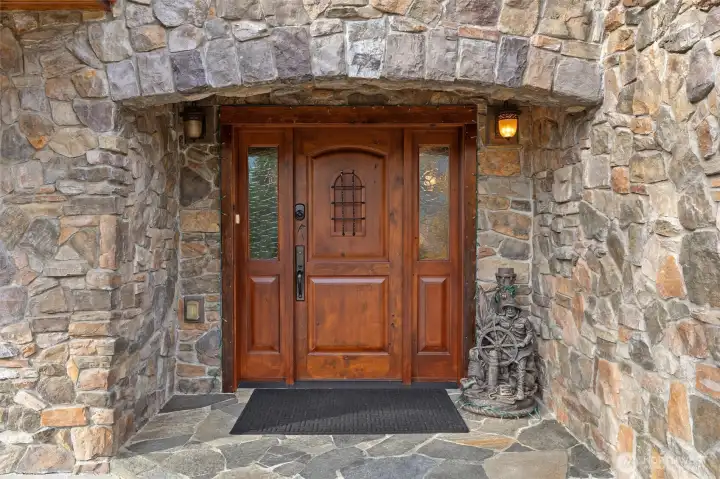 Stunning custom stone entry with slate floor and solid wood front door.
