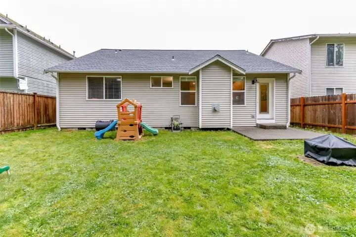 View of the back of the house. Fire pit stays and room to stretch out and play or BBQ and entertain.