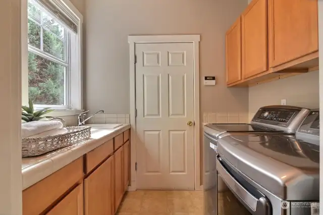 Slide through the mud room where a dreamy laundry is situated with folding counter, utility tub and storage cabinets.