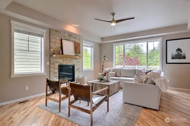 A light and bright living room with a stylish stone fireplace and refinished hardwood floors.