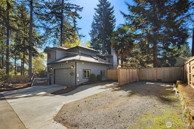 This gravel parking spot is part of the property with plenty of space for an RV or large boat. A small section of fencing visually separates it from the rest of the property.