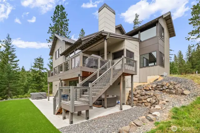 Great view of the main floor deck with stairs to the yard, patio on yard level, artificial turf  for easy care and great place for yard sports and then the hot tub ready for a relaxing dip.