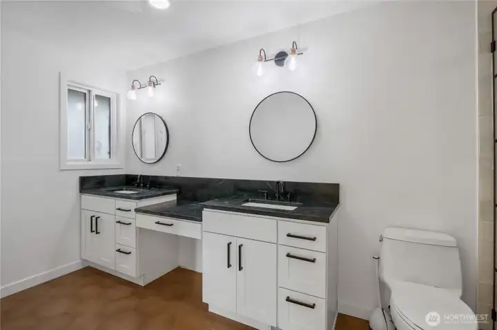 Primary bathroom featuring full tile shower, quartz countertops, and updated fixtures