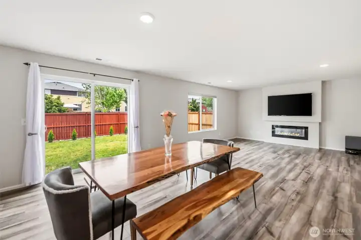 Sunlit dining space with a sliding glass door to the backyard, cozy fireplace, and an open layout ideal for entertaining.