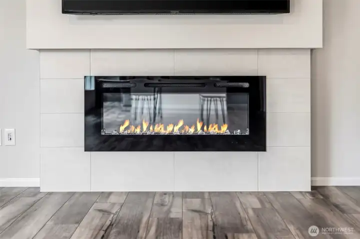 Modern linear electric fireplace set in a sleek tile surround—a cozy focal point with space above for a mounted TV.