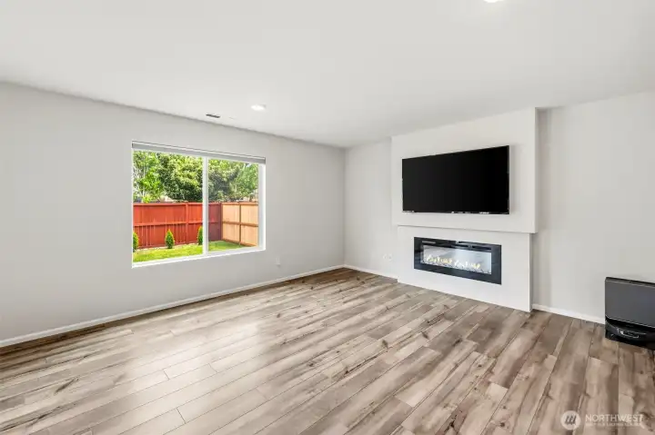 Spacious living room highlighted by a contemporary linear fireplace with tile surround and mounted TV space. Large window brings in plenty of light.