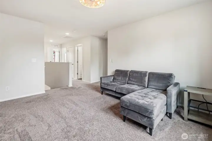 Flexible upstairs loft with plush carpet and access to the bedrooms — a great gathering space for the whole family.