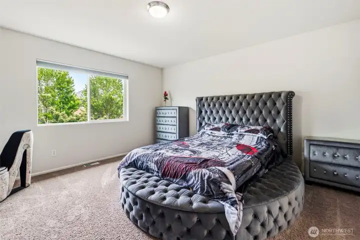 Spacious primary suite with a large window, soft natural light, and room for a king-sized bed.