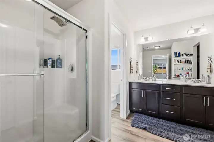 Private en-suite featuring a glass-enclosed shower, dual-sink vanity with quartz counters, and a separate water closet for added privacy.